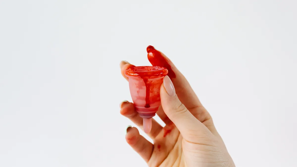 Hand holding a red menstrual cup