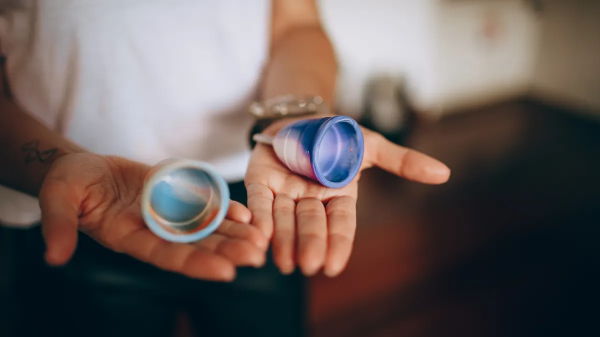 Hands holding two menstrual cups