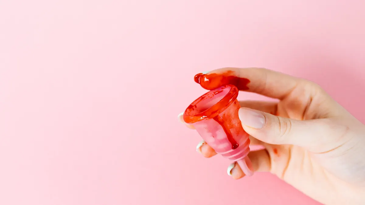 Hand holding a red menstrual cup